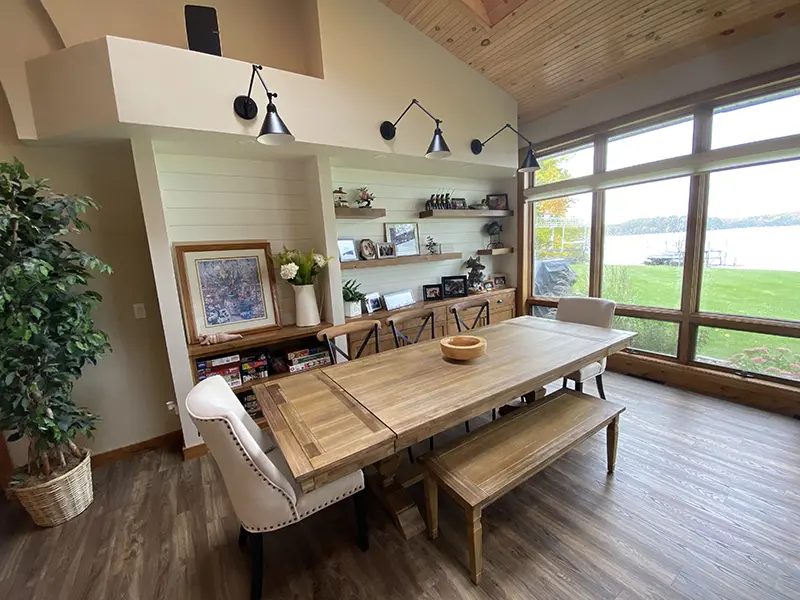 wooden dining table with chairs and a bench in front of a wall with built-in shelves and unique overhead lighting interior design by Interiors of Distinction